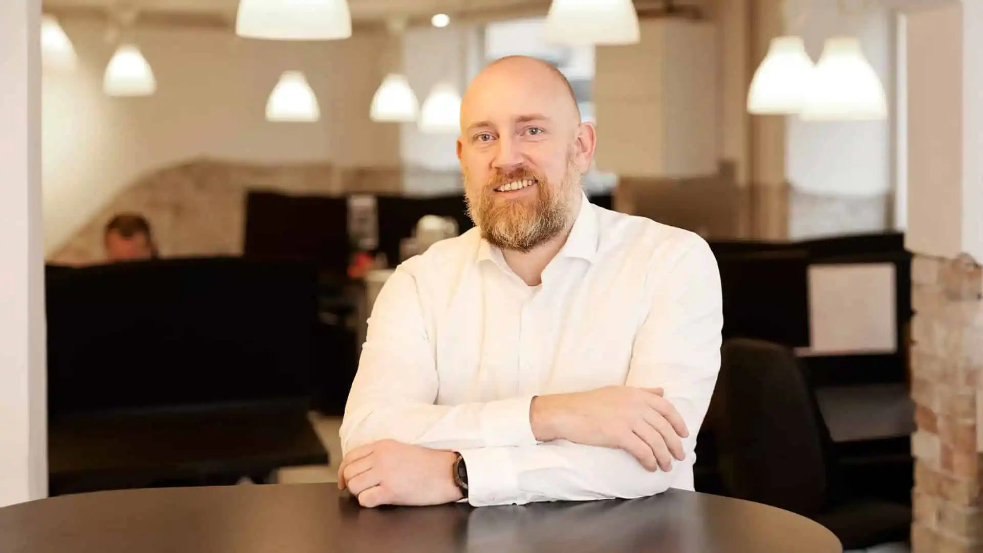 Marketing rådgiveren står ved et bord og smiler, han hjælper sine kunder med at vælge de rigtige samarbejdsparterne, til de rigtige opgaver i den rigtige rækkefølge, så hans kunder får maksimalt afkast af deres marketing investeringer. Rådgiveren leverer værdifuld og objektiv rådgivning. Den rådgivning virksomheden har brug for, for at kunne nå sine vækstmål.